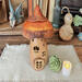 A fairy house mushroom made with a real dried gourd. Windows are carved out of the gourd shell. The top is burnt orange, the bottom is tan.